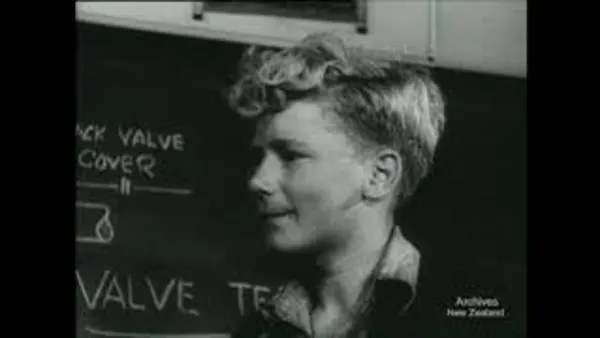 Black and white photo of a smiling boy with short blonde hair smiling and a side pose, some text written on the left