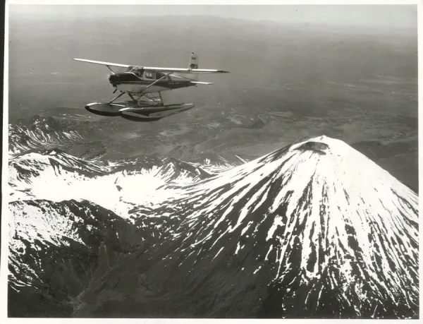 Top view photo of a snow clad mountain and a floatplane flying in the sky