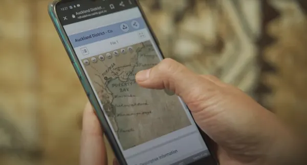 A hand holding a phone with a map on a brown blurred background  
