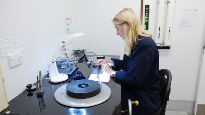 a woman sits at a desk and inspects a film
