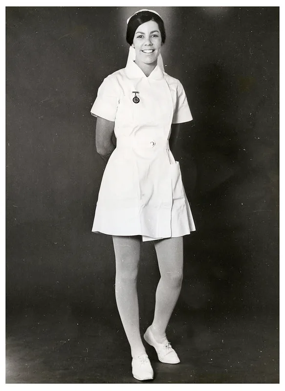 black and white image of a young woman in a white nurses uniform