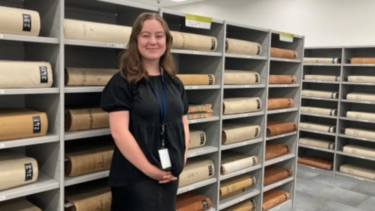 A smiling woman in a black dress standing in the repository