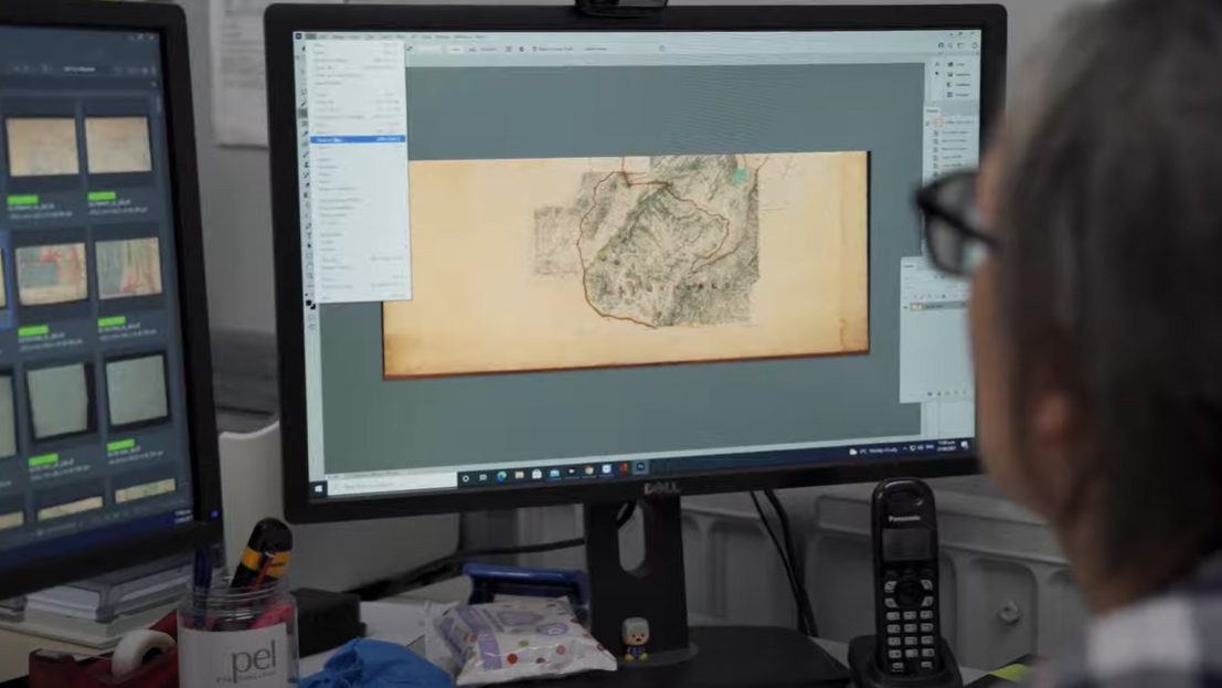 A digitisation technician looks at an image of a map on a computer screen