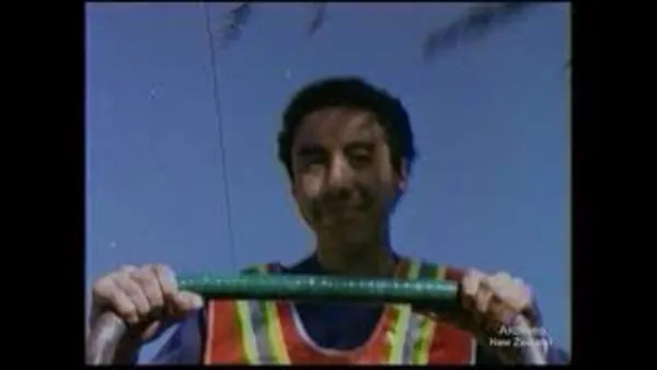 A still from 'Running for Empties'. A young man wearing a hi-vis vest holds the handlebar of a trolley.