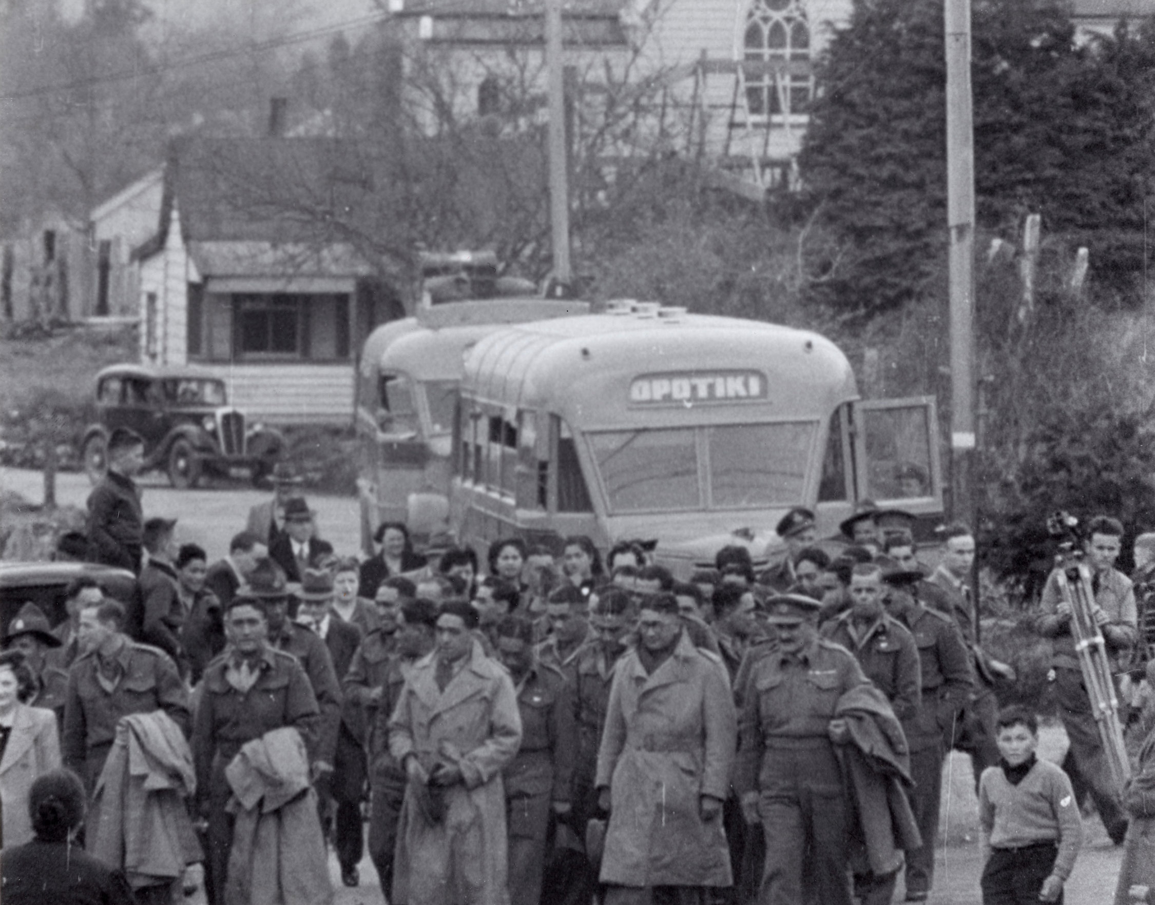 Members of the Māori battalion walking. Behind them is a bus labelled 'Opotiki'