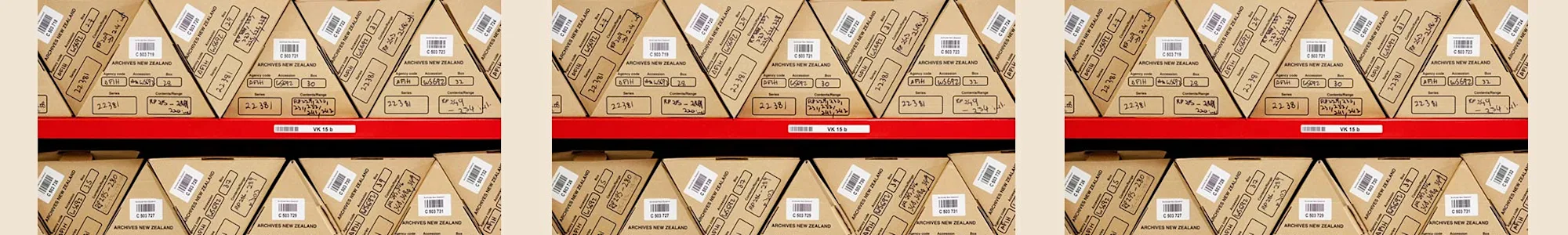 Repeated images of ends of triangular shaped boxes on red shelving.