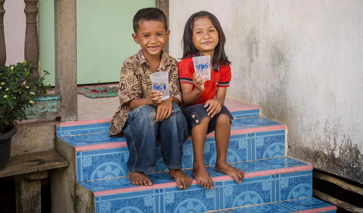 Enfants souriant et tenant un verre d'eau purifiée