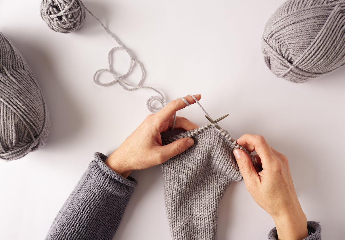 Hands knitting with grey yarn