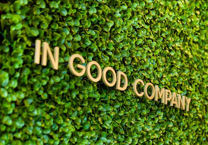 Words "IN GOOD COMPANY" on top of wall of small, green leaves