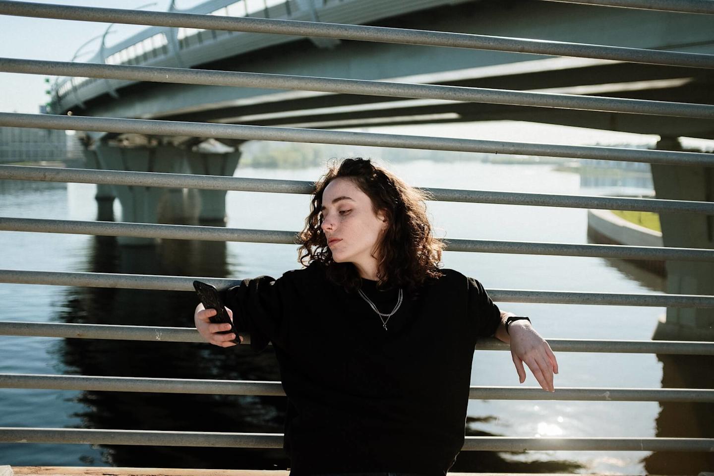 Person looking at phone while leaning on railing