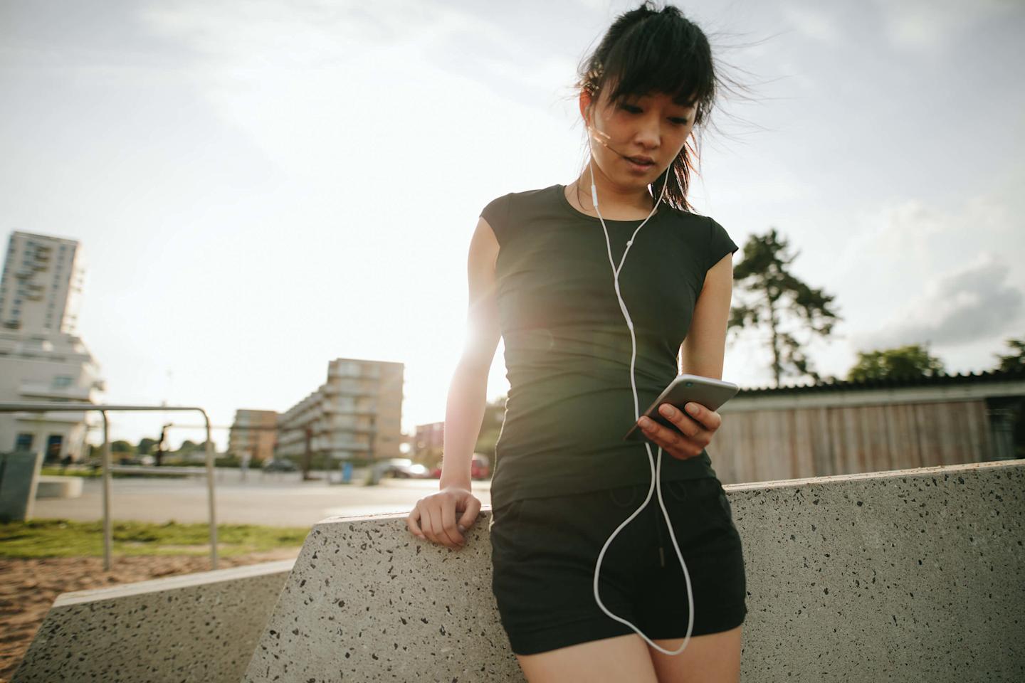woman in workout clothes checking fitness app on phone
