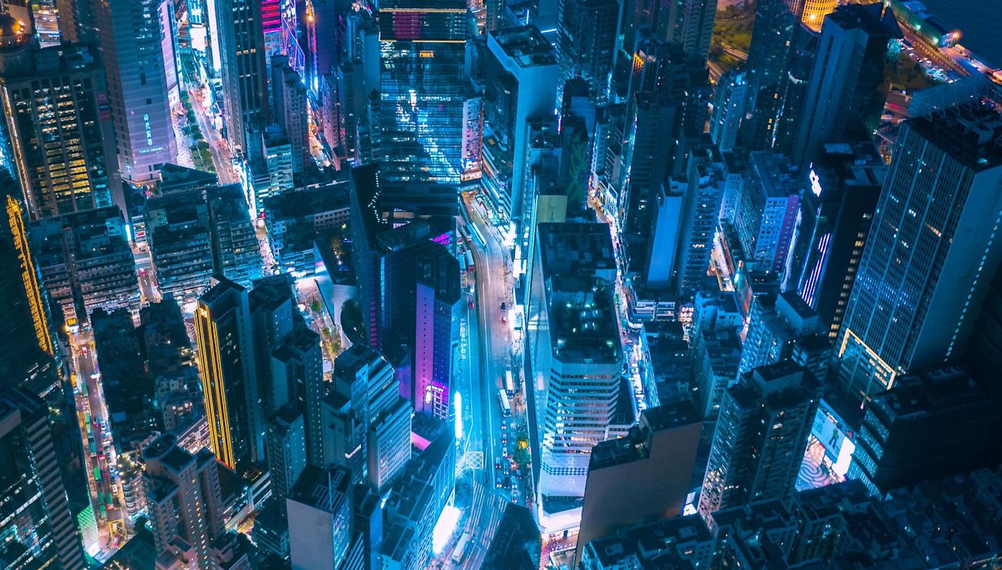 A bust city at night lit up by lights and cars ina. blue/purple hue.