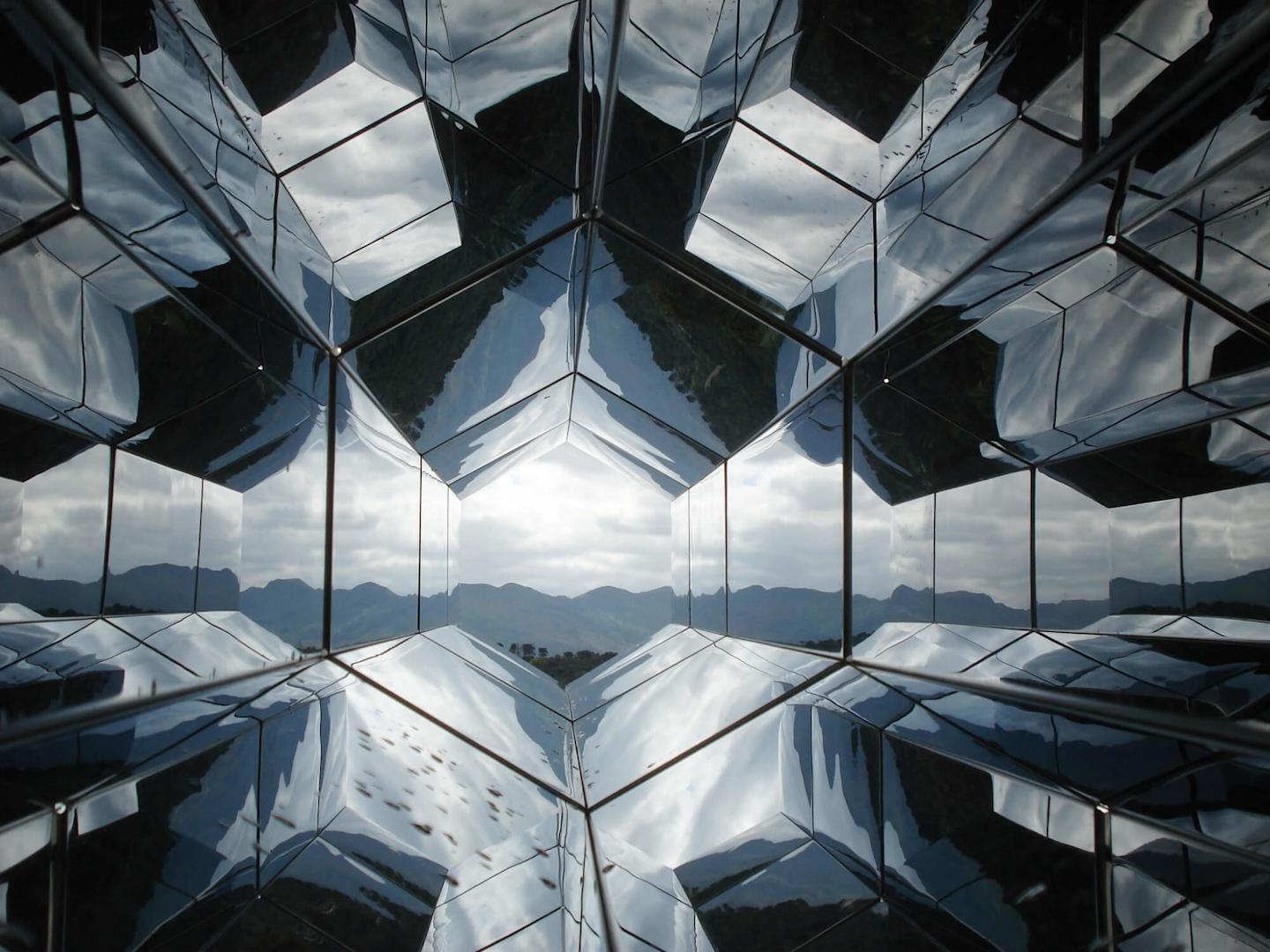a kaleidoscope-like image looking to mountains through a metal-like structure.