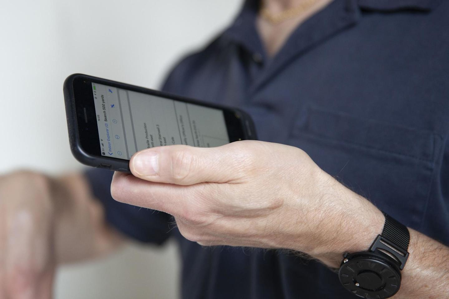 Image of person holding phone with Blindsquare app in it.