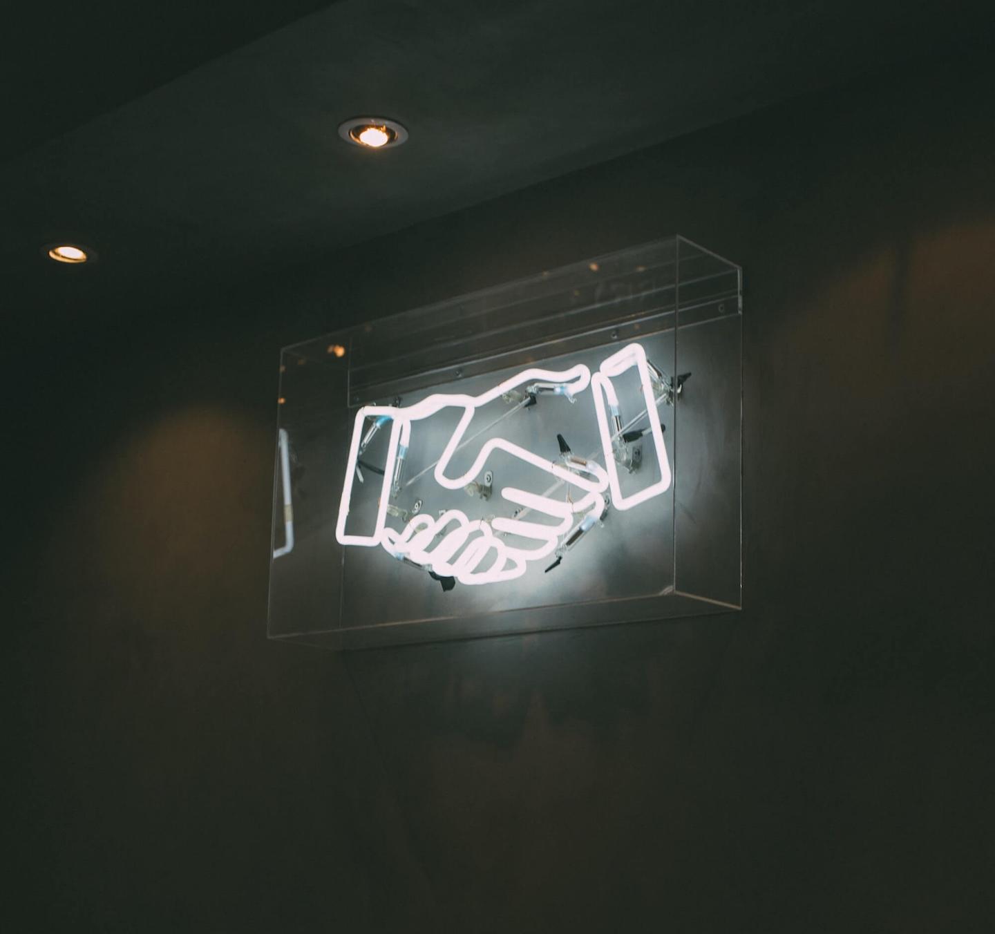 Neon sign of hands shaking