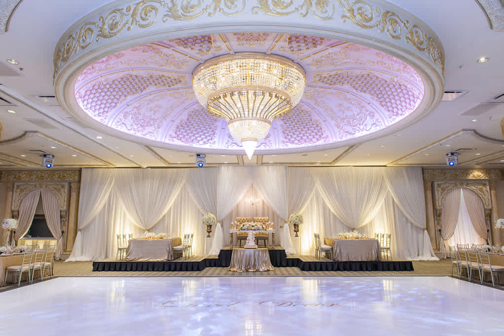 A dance floor in front of the head table at a wedding with a chandelier above.