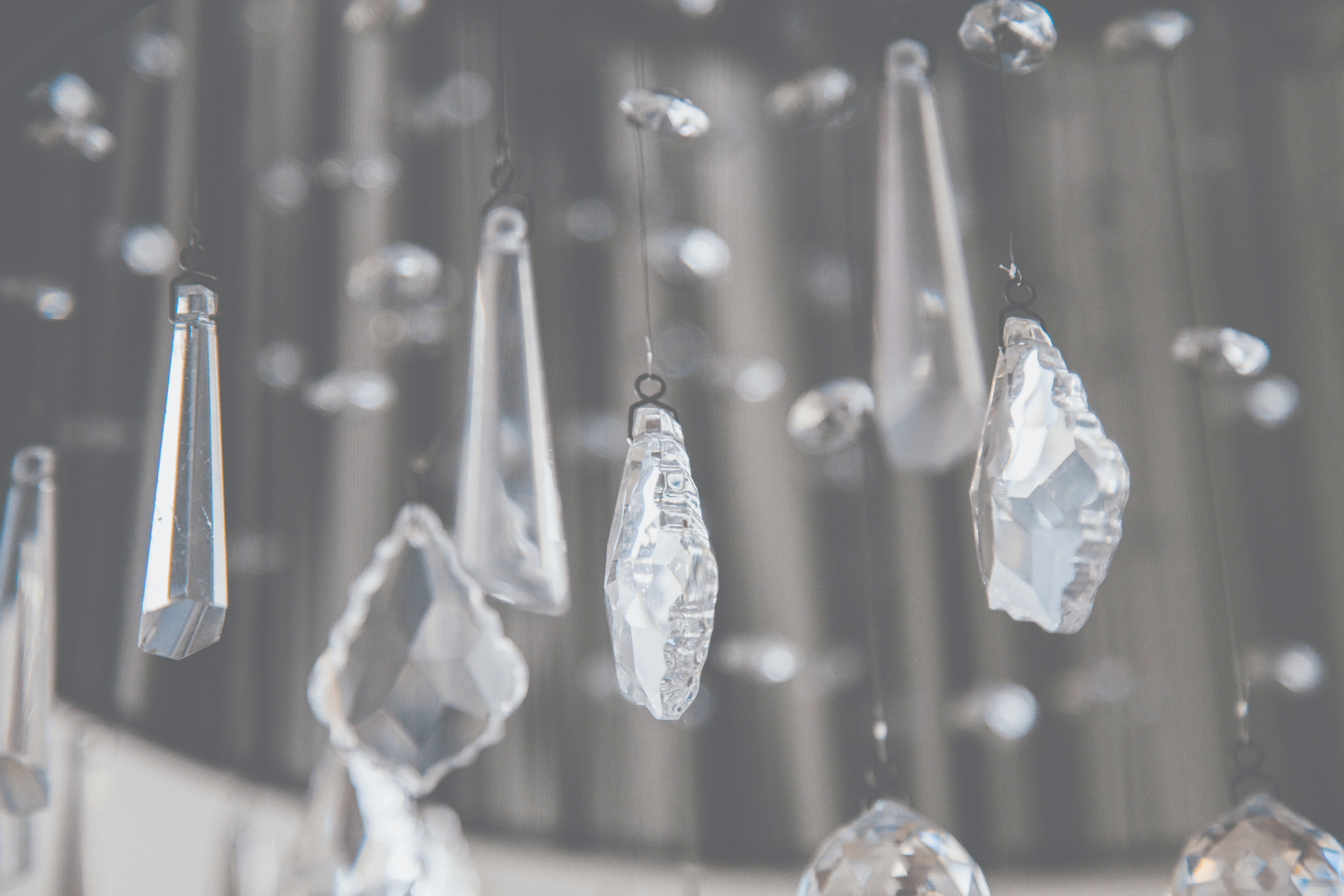 A close-up of a clear, crystal chandelier and its individual pieces of various shapes.
