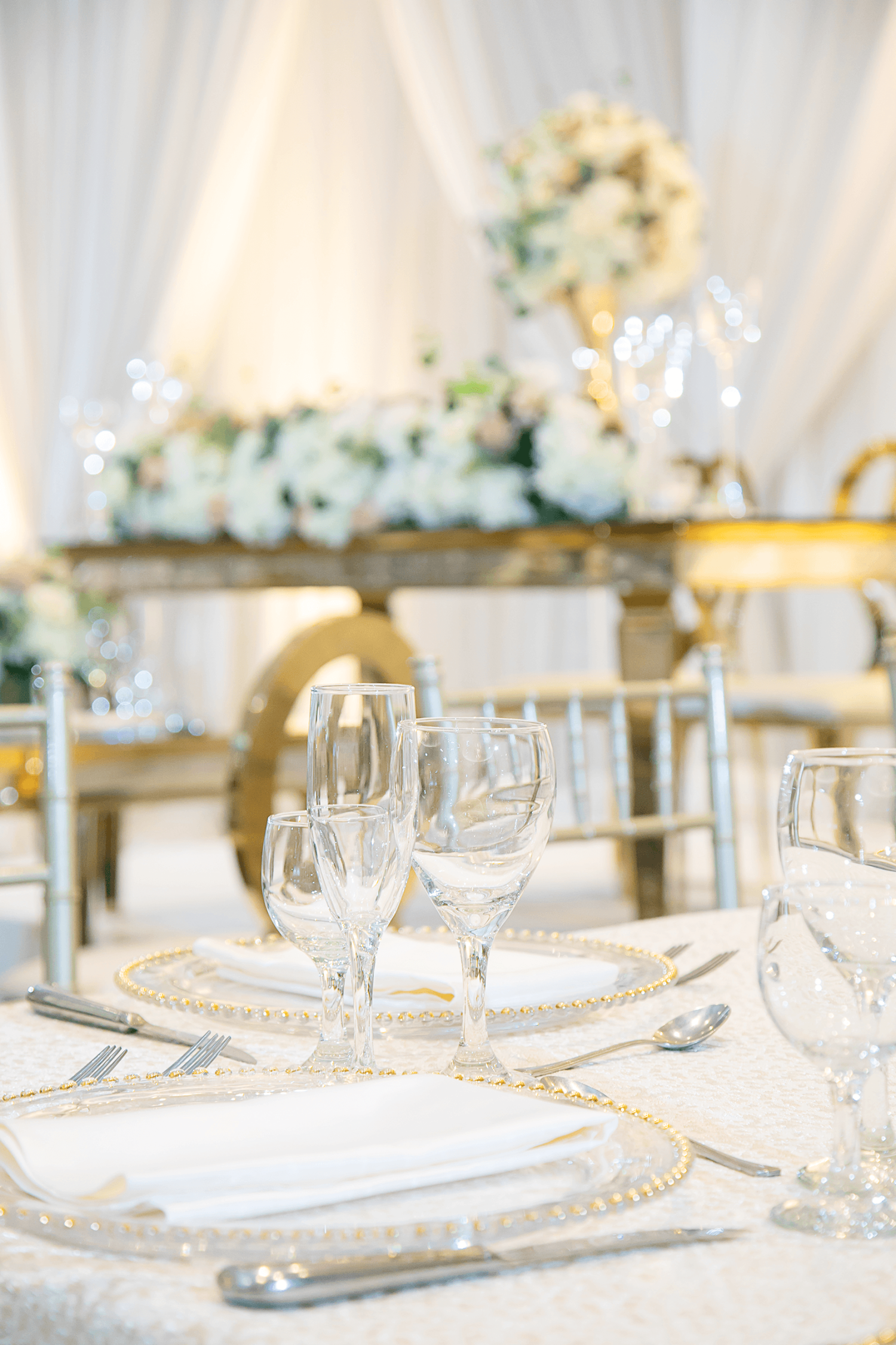 A close up of a table setting at a wedding with white and gold accents at Paradise Banquet Halls.