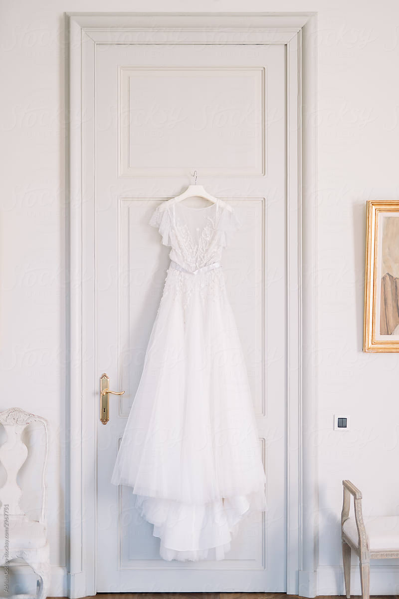 A white wedding dress hung on the back a closed door.
