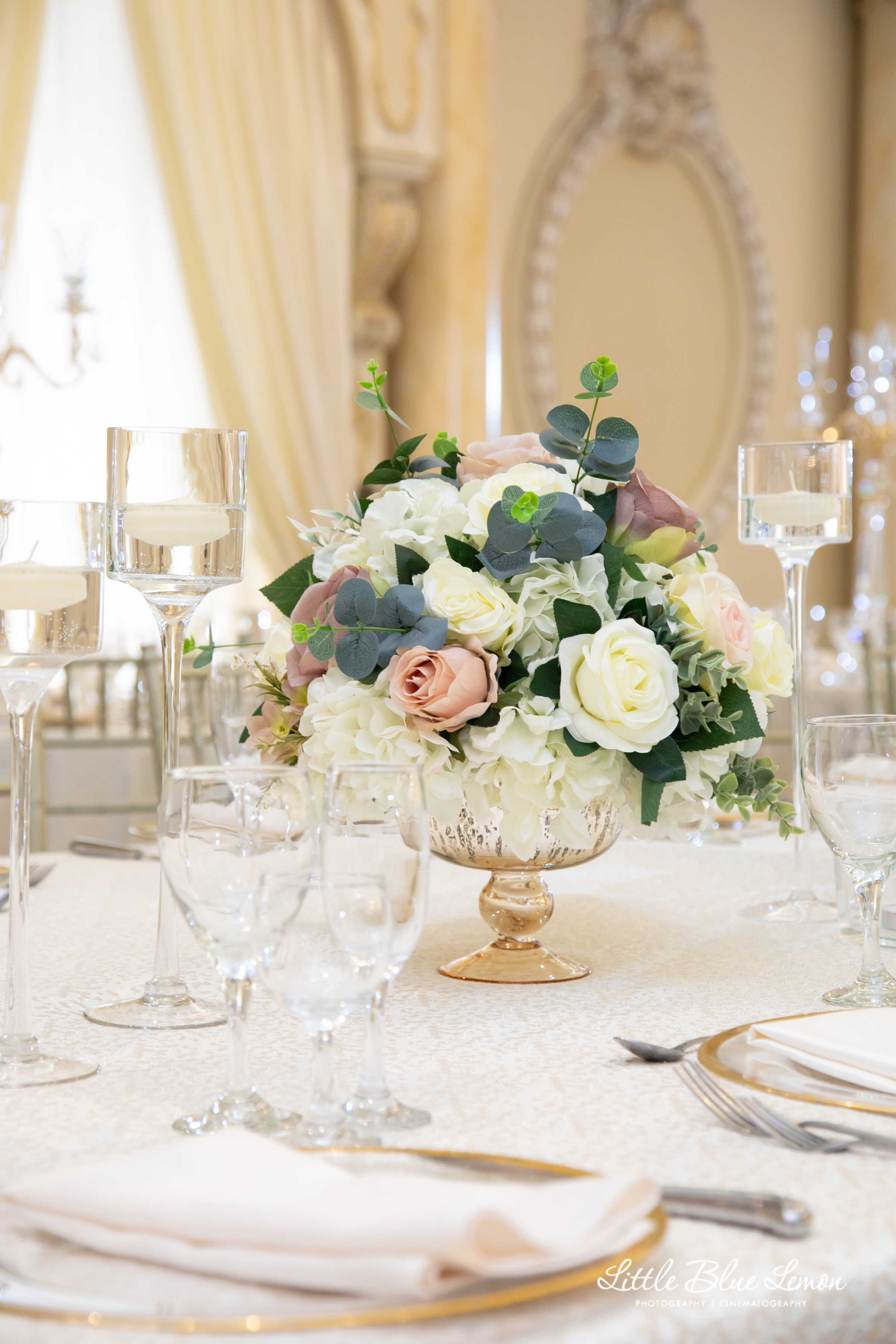 A flower arrangement set on a table with silverware and a white linen table sheet.