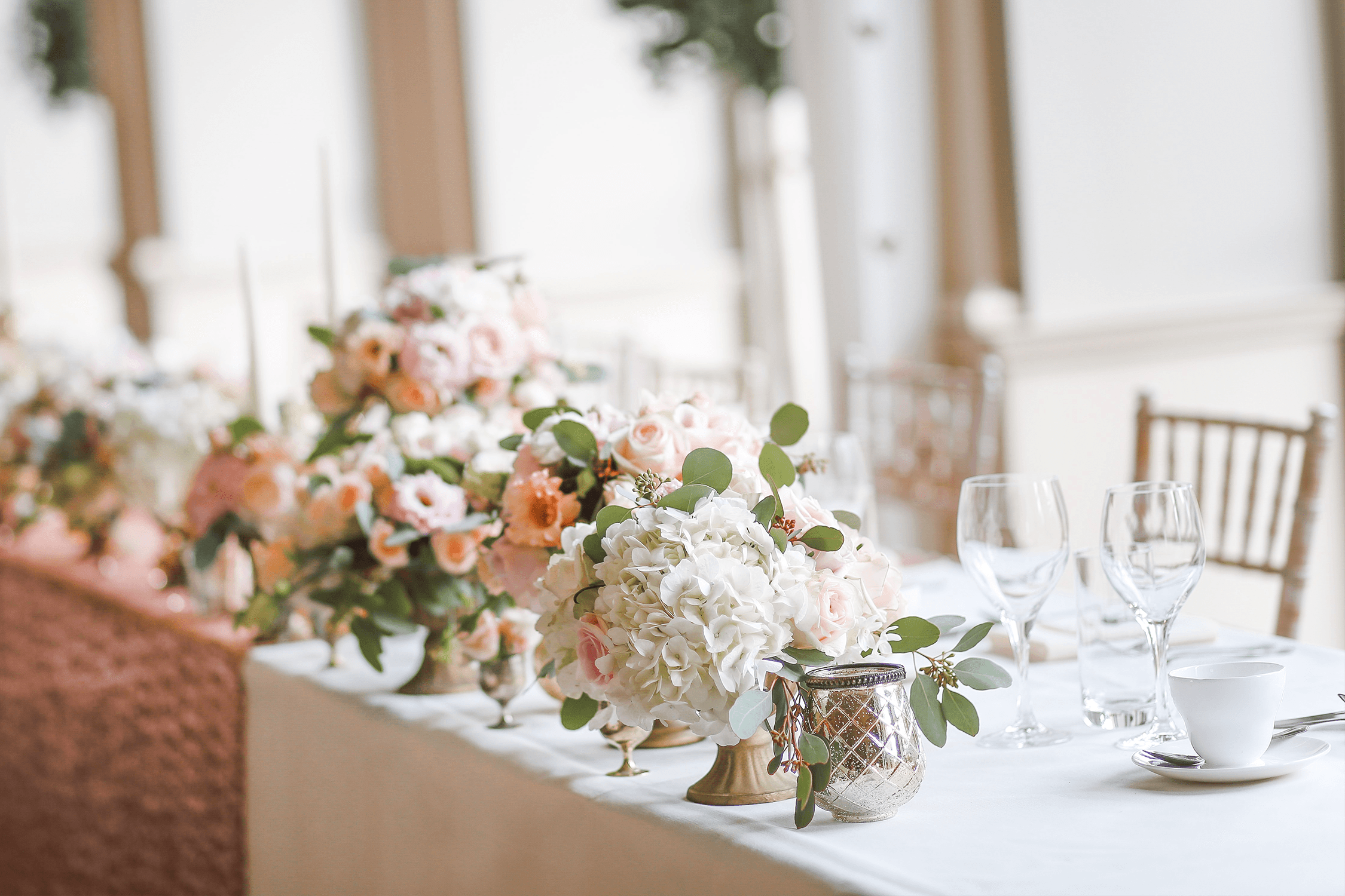 The head table at a wedding with white and pink flowers
