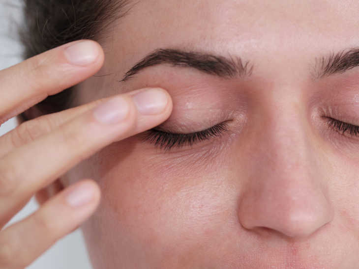 Frau trägt Neurodermitis-Pflege auf die Augenlider auf