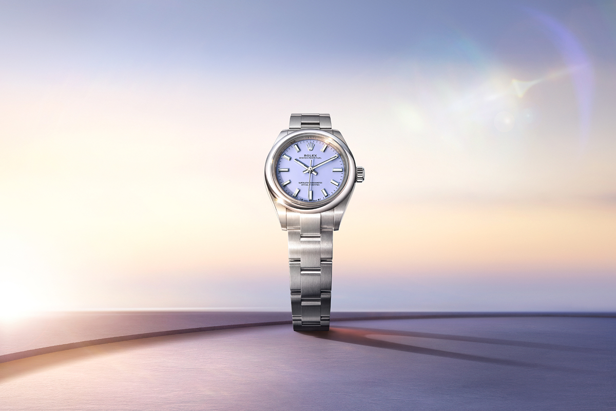 A gold wristwatch with a blue face and rotating bezel against a gradient blue background. The watch features luminous markers and hands, and a date display at the 3 o'clock position. The brand name "Rolex" and "Deepsea" are visible on the dial.