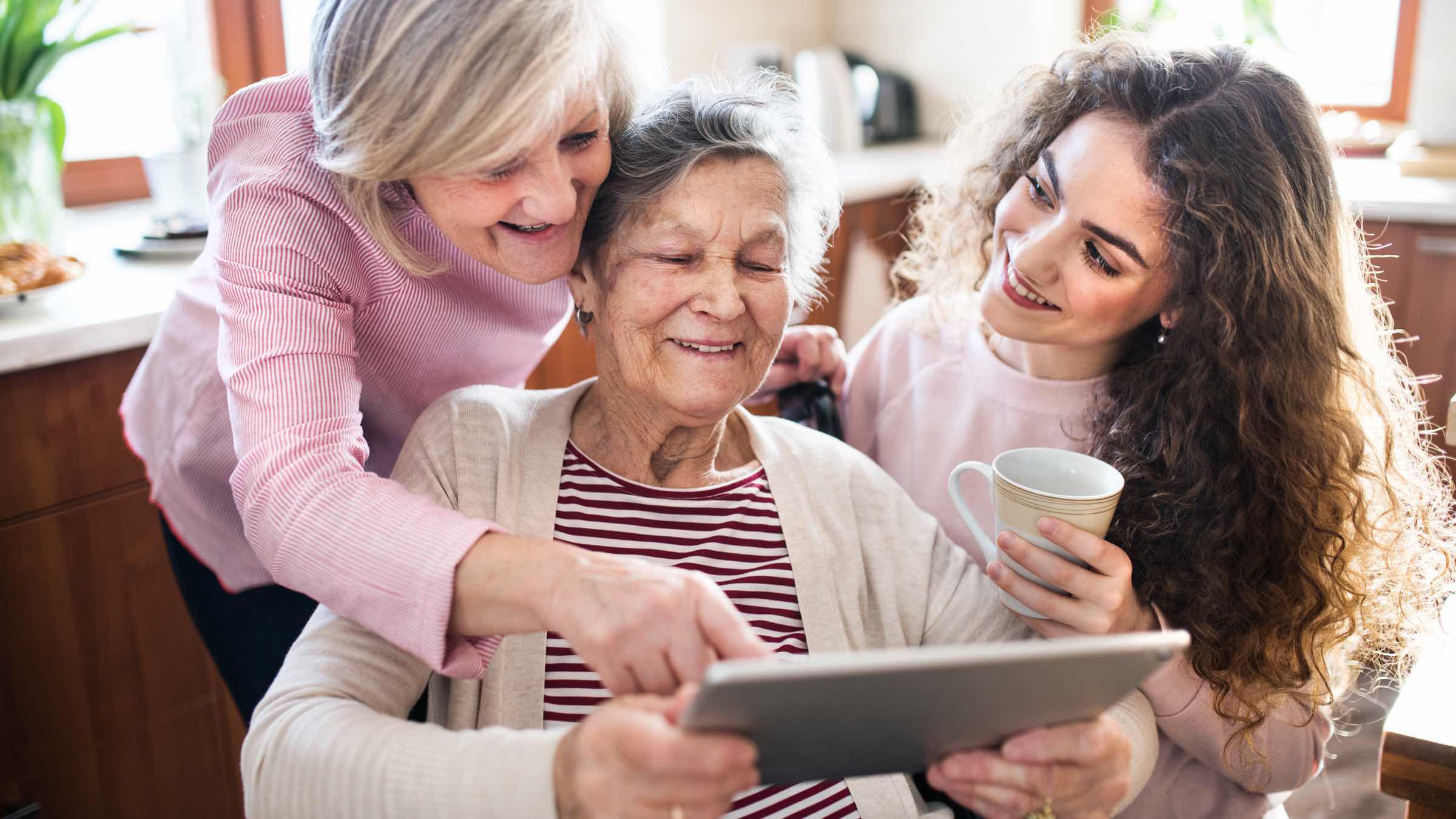 Eine Oma erfreut sich mit ihrem Kind und Enkelkind an einem Senioren Tablet.