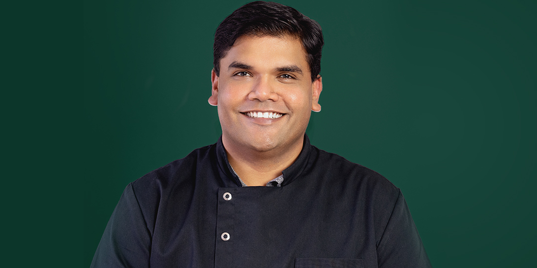 Dr. Kumar, senior dentist at Vogue Dental Studios, smiling in black shirt.