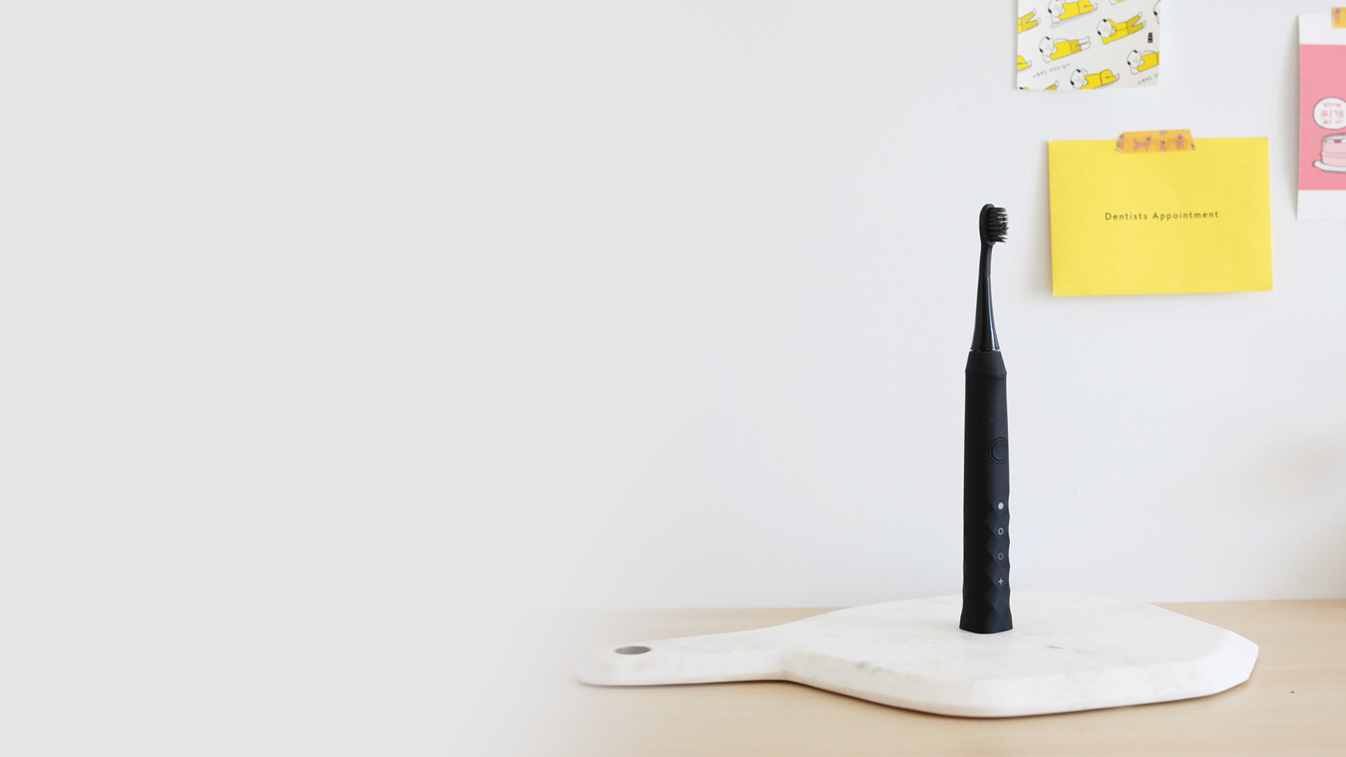 Black electric tooth brush on desk with sticky notes.