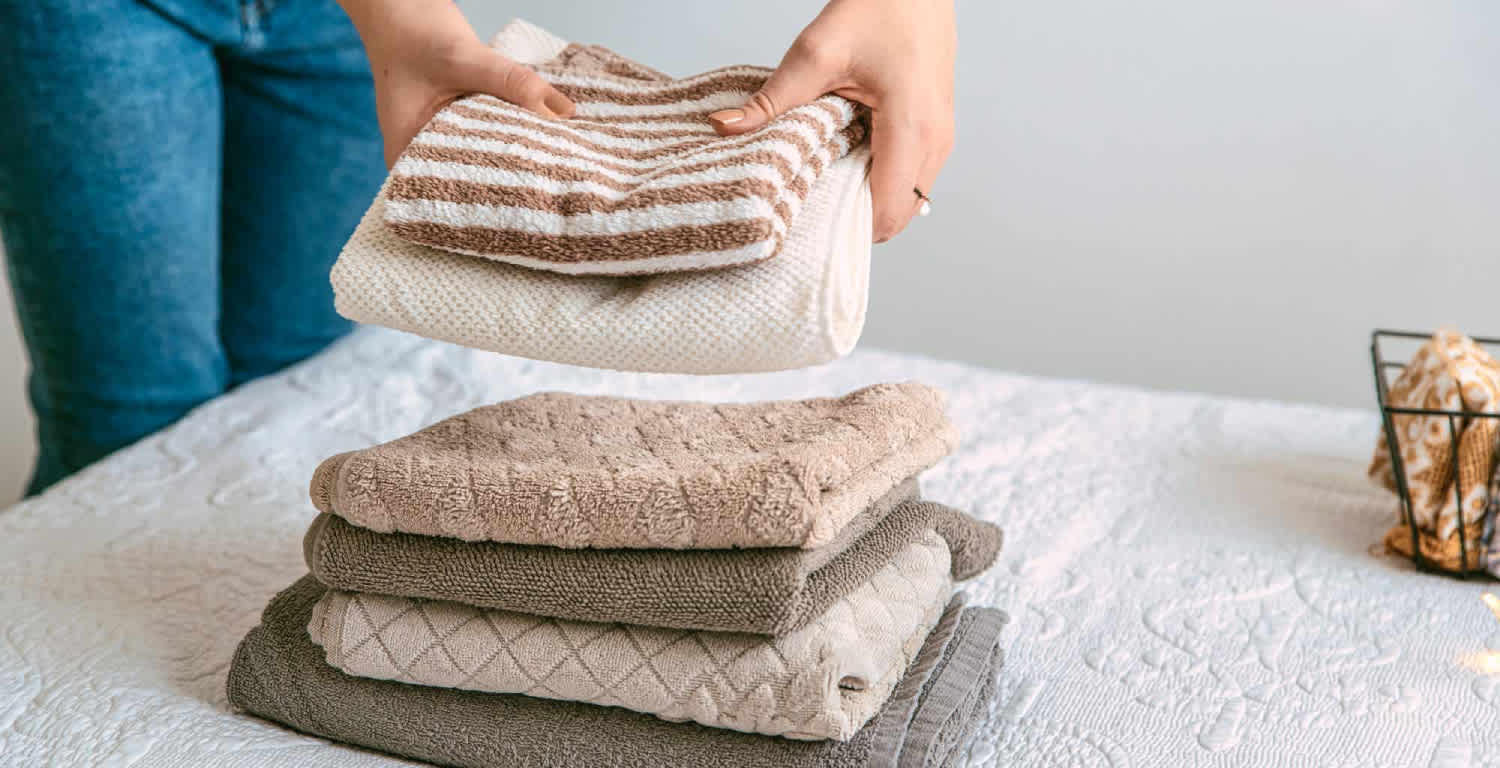 Una mujer haciendo una pila de ropa pila sobre la cama