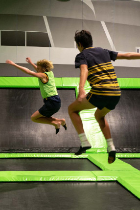 Two boys bouncing on trampolines