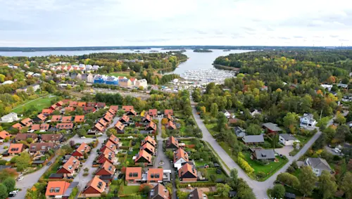 Flygvy över Täby med villaområde, grönska och närhet till vatten i attraktiv och naturnära boendemiljö.