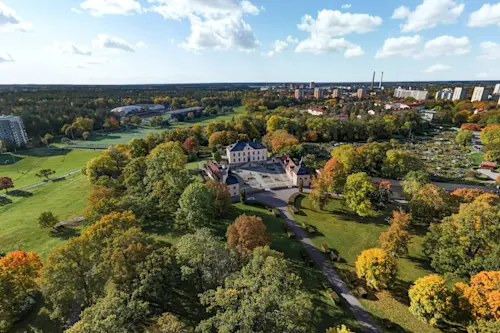 Flygvy över Hässelby-Vällingby med Mälaren, småbåtshamn, grönska och bostadsområden i västra Stockholm.