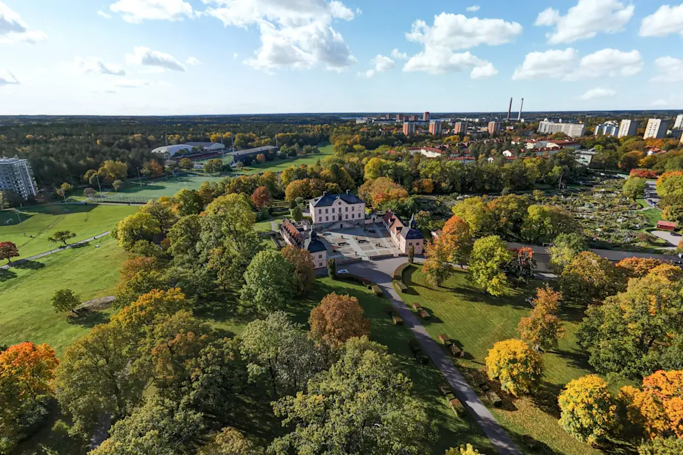 Flygvy över Hässelby-Vällingby med Mälaren, småbåtshamn, grönska och bostadsområden i västra Stockholm.