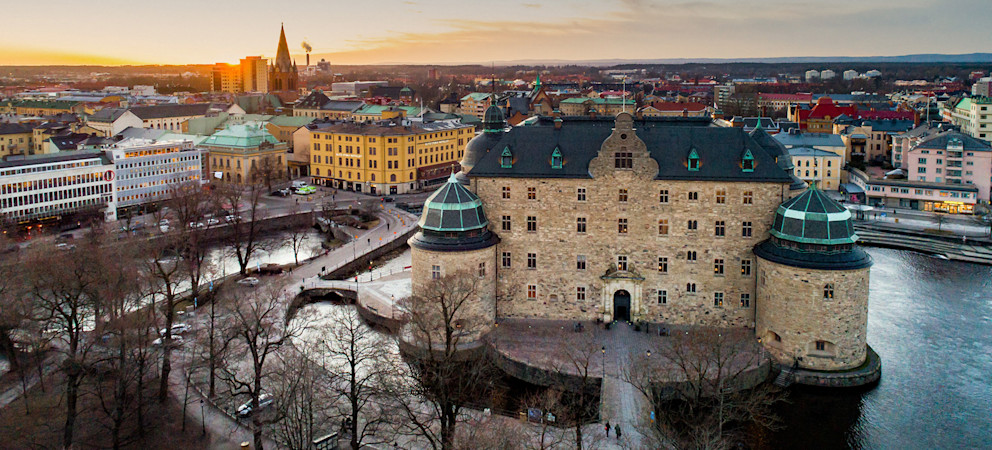 Vyn över Örebro slott i bakgrunden och Svartån i förgrunden och Olaus Petri kyrka i bakgrunden.
