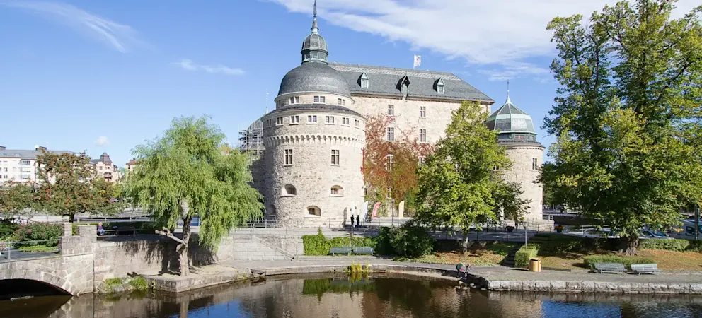 Vyn över Örebro slott i bakgrunden och Svartån i förgrunden och Olaus Petri kyrka i bakgrunden.