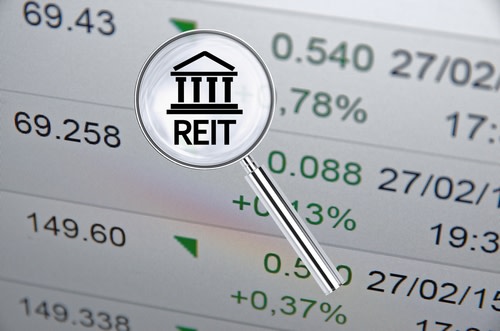 Magnifying Lens Over Background With Building Icon and Text REIT