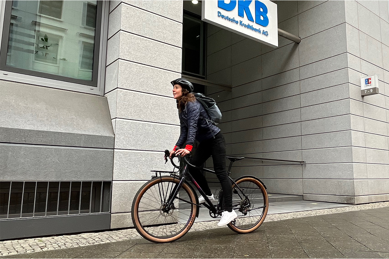 Frau fährt auf ihrem Fahrrad an der DKB Zentrale vorbei