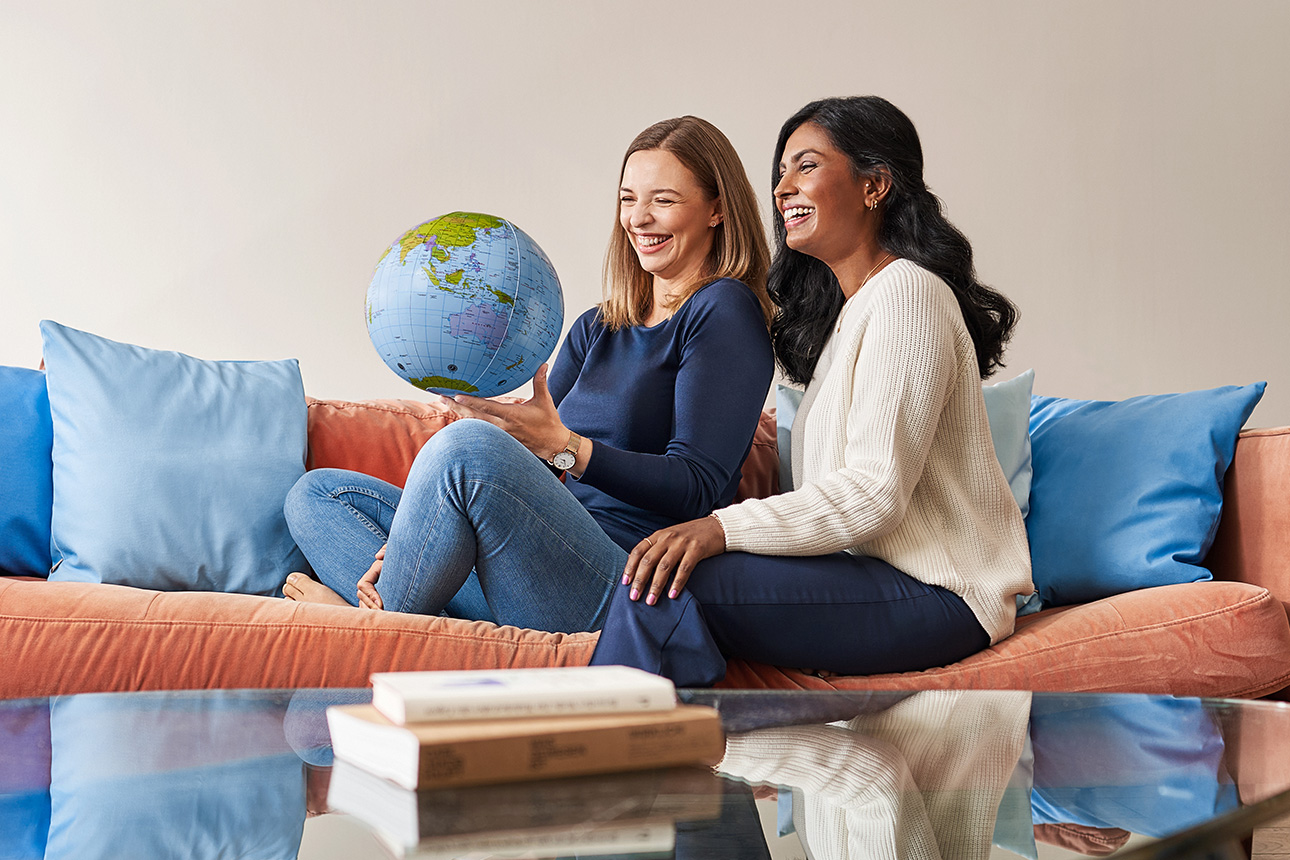 zwei Frauen auf Sofa mit Weltkugel