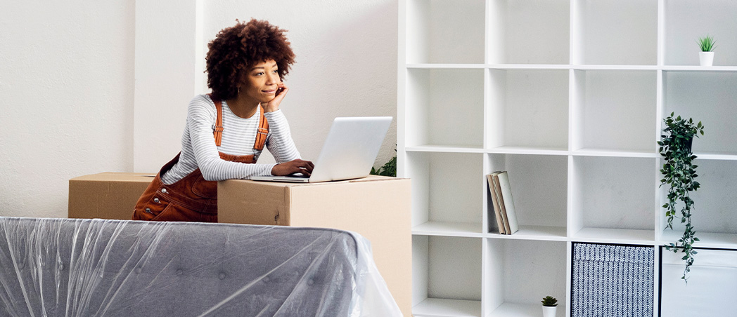 Eine Frau steht am Laptop in einer neuen Wohnung