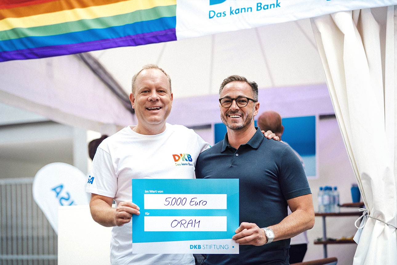 DKB-Mitarbeiter Karsten übergibt Spendenscheck an Geflüchtetenorganisation