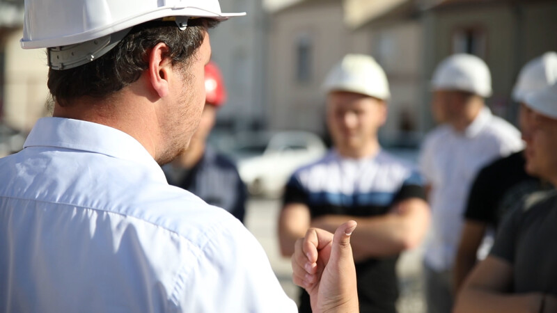 Un encadrant parle à des compagnons sur une zone de travaux.