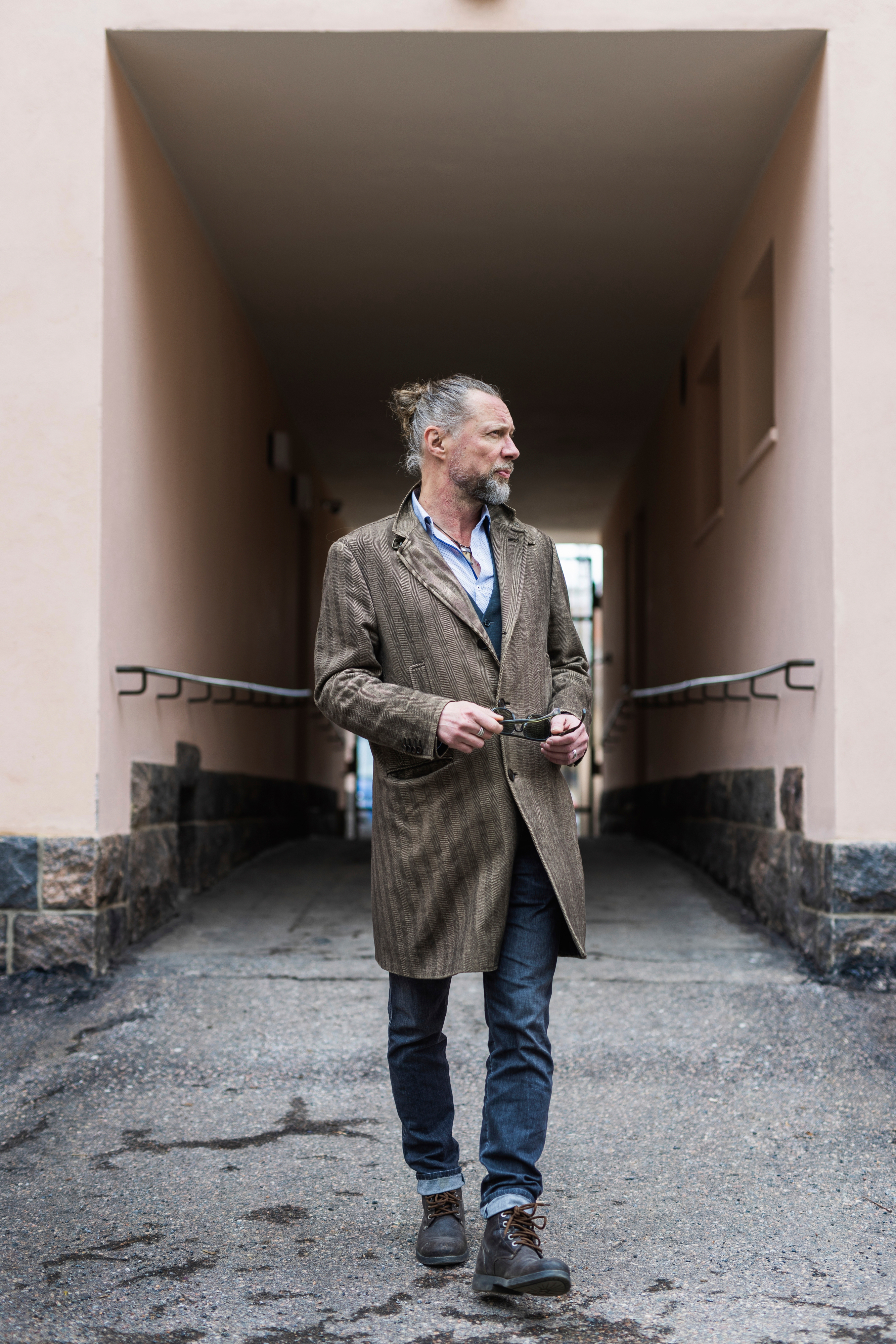 Antti Reini kävelee porttikäytävässä ja katsoo sivuun