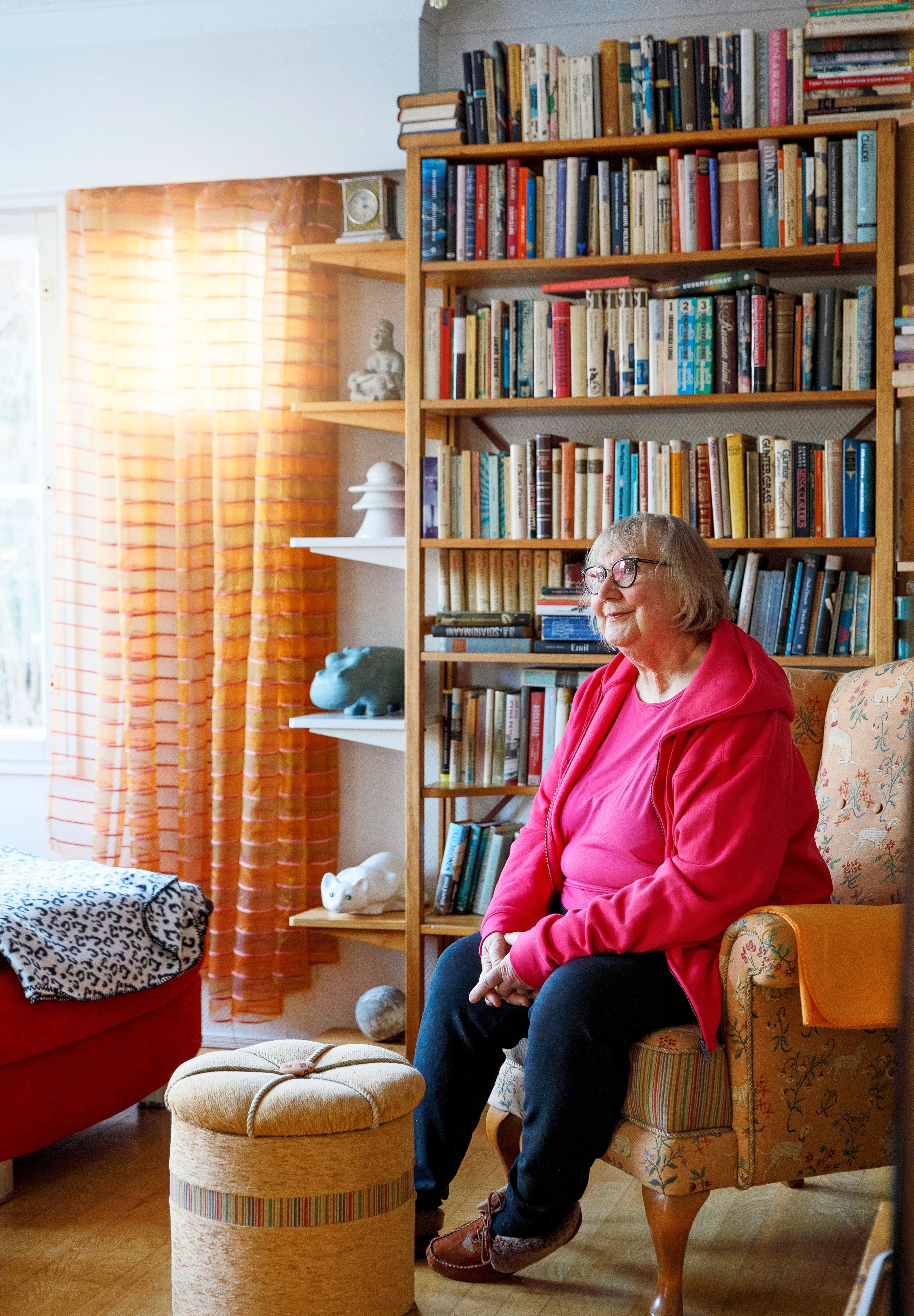 Anneli Kanto istuu nojatuolissa, taustalla kirjahylly