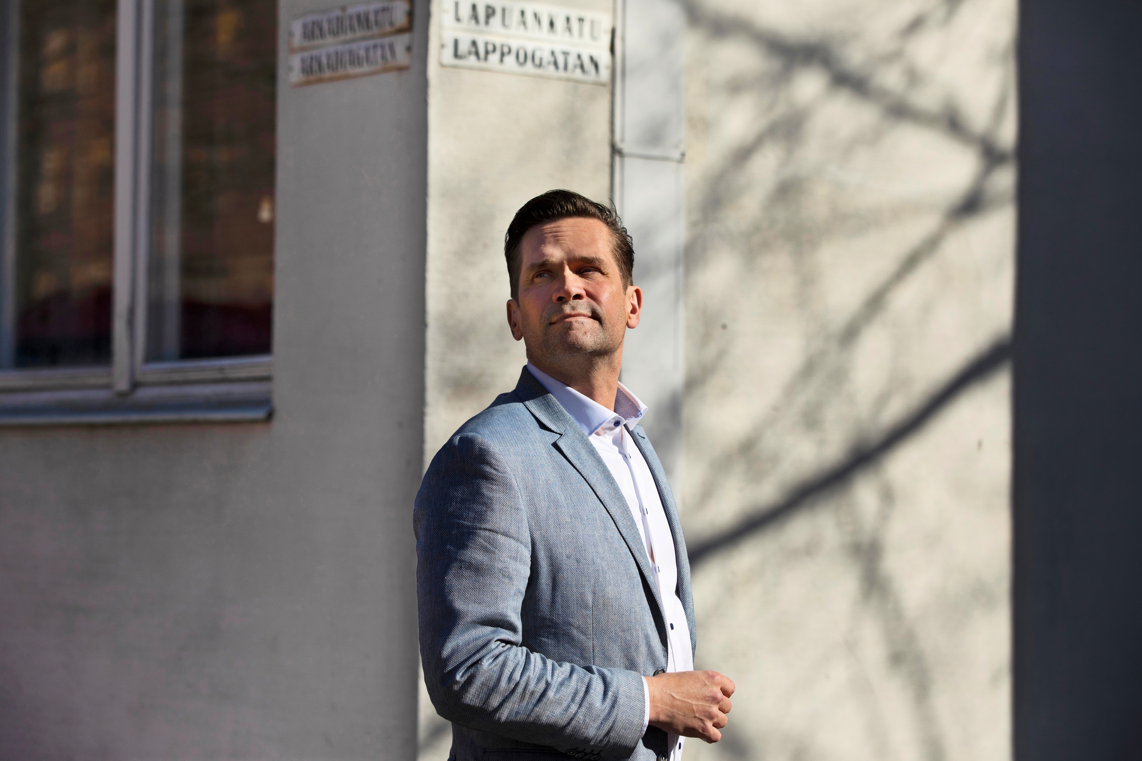 Mika Aaltola seisoo kerrostalon kulmalla ja katsoo yläviistoon.