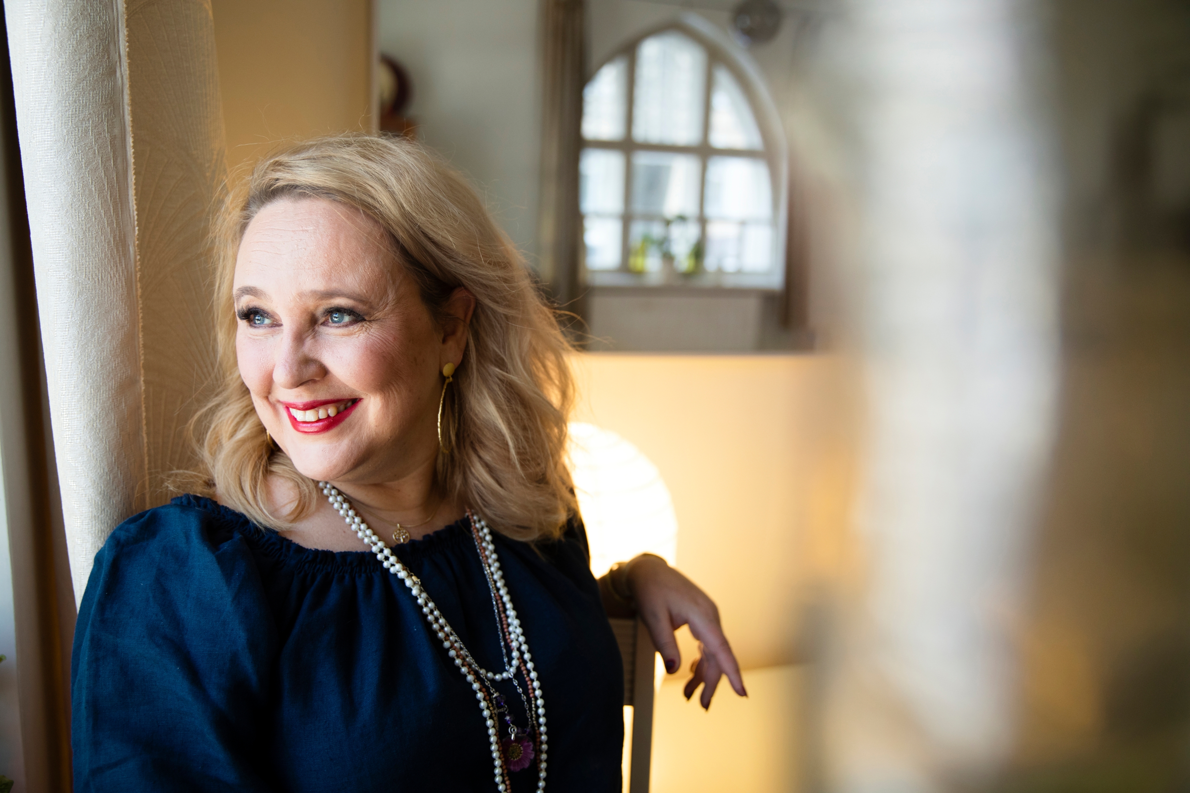 Eeva Pesonen hymyilee, katsoo ulos ikkunasta