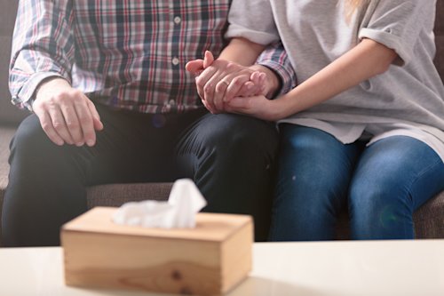 Family holding hands in support with tissue box