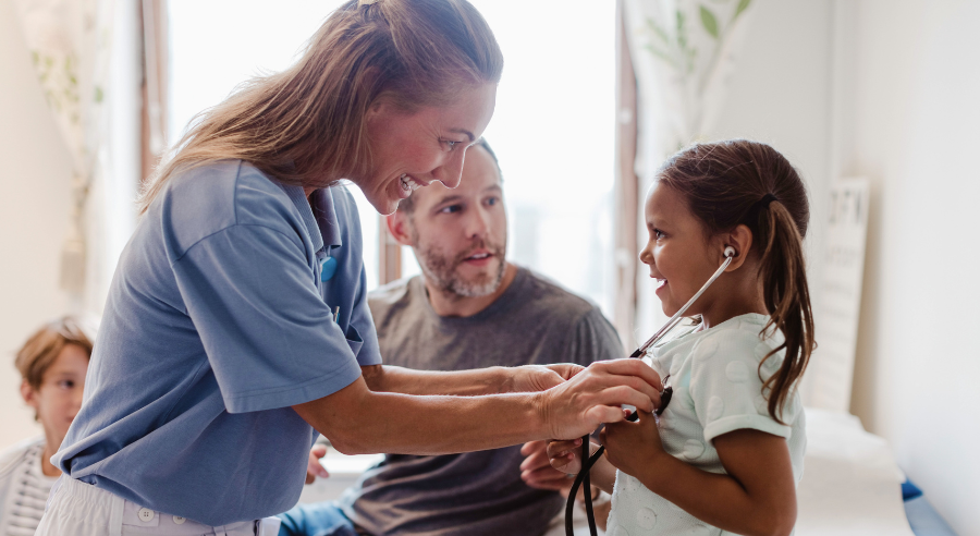Doctora atendiendo a una niña pequeña que está sentada junto a su padre
