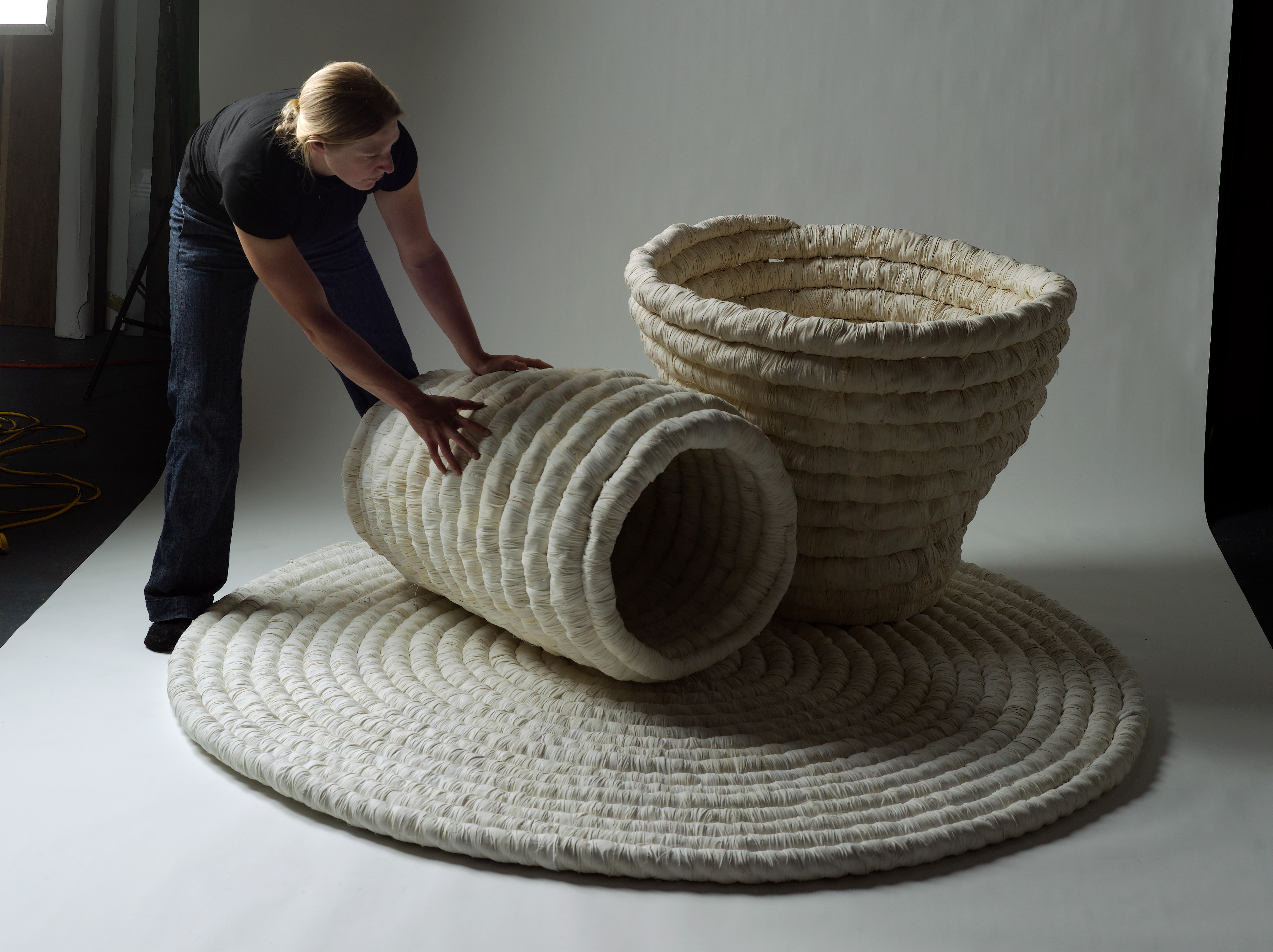 A photo of Sally behind an oversized fibre artwork, looking down